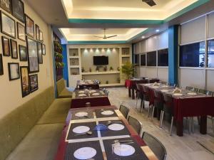 HOTEL DEO VOLENTE في Sibsāgar: غرفة طعام بها طاولات وكراسي وتلفزيون