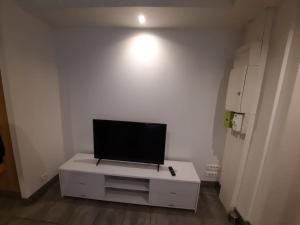 uma sala de estar com televisão numa parede branca em Charmante petite maison em Cholet