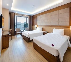 a hotel room with two beds and a desk at Eden Star Saigon Hotel in Ho Chi Minh City