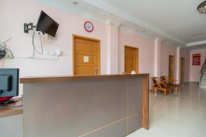 a lobby with a reception desk and a tv on a wall at RedDoorz Syariah near Transmart Padang in Padang
