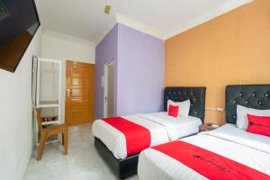 a hotel room with two beds and a flat screen tv at RedDoorz Syariah near Transmart Padang in Padang