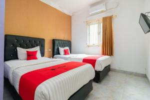 two beds in a room with red and white at RedDoorz Syariah near Transmart Padang in Padang
