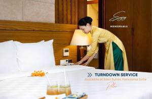 Una mujer está haciendo una cama en una habitación de hotel en Eden Star Saigon Hotel, en Ho Chi Minh
