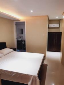a bedroom with a white bed and a kitchen at Avana Hills Boracay Prime Family Suite in Boracay