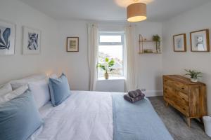 a bedroom with a bed with blue pillows and a window at Bright & beautiful 4 bedroom house with sea views in Castletown