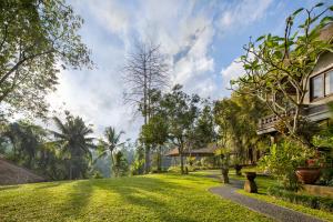 une maison avec une cour herbeuse à côté d'un bâtiment dans l'établissement The Allure Ubud Villas, à Ubud