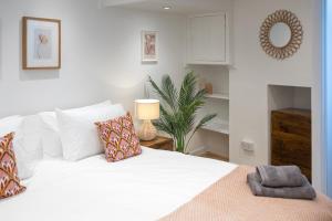 a bedroom with a white bed with pillows and a plant at Bright & beautiful 4 bedroom house with sea views in Portland