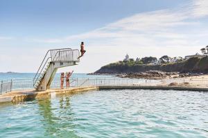 una persona saltando de una escalera al agua en Maison au calme et proximité plage. en Saint-Quay-Portrieux