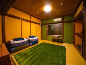 a room with two beds and a green rug at Guest House Tokiwa in Fujinomiya