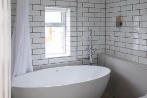 a white bathroom with a tub and a window at Bright & beautiful 4 bedroom house with sea views in Portland +28 photos