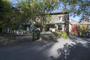 a stone house with a stone wall and a tree at 2 Dixon Ground Coniston in Coniston