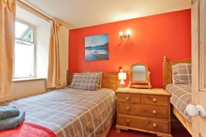 a bedroom with orange walls and a bed and a mirror at 4 Dixon Ground Coniston in Coniston