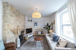 a living room with a couch and a stone wall at Bright & beautiful 4 bedroom house with sea views in Portland