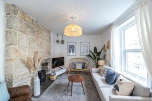 a living room with a couch and a stone wall at Bright & beautiful 4 bedroom house with sea views in Castletown