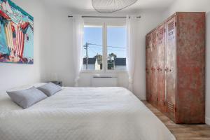 a white bedroom with a large bed and a window at Belle maison pour 11 - Jardin - Détente in La Baule