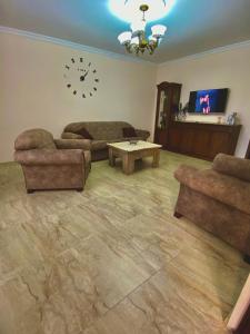 a living room with a couch and a table and a clock at Family Home in Batumi