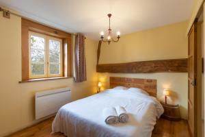 Un dormitorio con una cama blanca con toallas. en Gite Le Foineau - Maison avec Piscine, en Bresse-sur-Grosne
