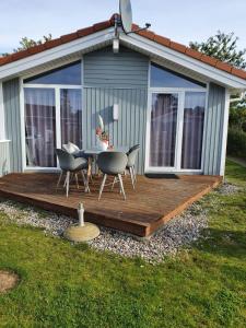 eine Holzterrasse mit Stühlen und einem Tisch vor einem Haus in der Unterkunft Bootshus - Strandpark 15 in Grömitz