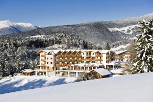 un grande hotel nella neve tra le montagne di Hotel Chalet Tianes - Alpine Relax a Castelrotto