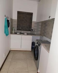 a kitchen with a sink and a washing machine at Sebs Chalet in Hartbeespoort