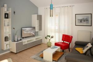 a living room with a television and a red chair at Ferienwohnungen Buchenweg in Ostseebad Sellin