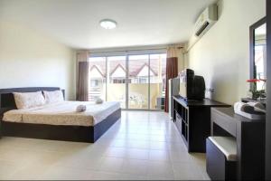 1 dormitorio con 1 cama y TV en Kata Beach Guesthouse en Kata