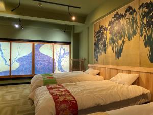 - une chambre avec 2 lits et un tableau mural dans l'établissement Osaka Ukiyoe Ryokan, à Osaka