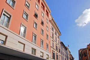 a tall orange building with windows on a street at Adamas Luxury Suite in Rome