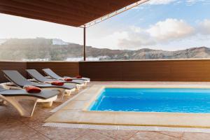 a resort pool with lounge chairs and a view of the mountains at Moser Living Premium Apartments in Mogán