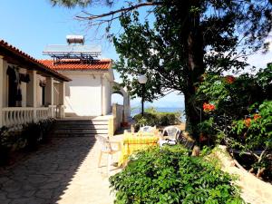 a patio with chairs and a tree and a house at IONIO Apartments in Lefkímmi