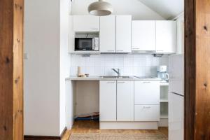 a white kitchen with a sink and a microwave at Upper floor studio with a sea view in Helsinki