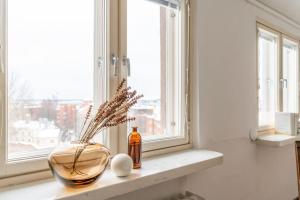 a vase sitting on a window sill with a bottle of oil at Upper floor studio with a sea view in Helsinki