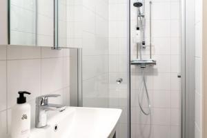 a white bathroom with a sink and a shower at Upper floor studio with a sea view in Helsinki