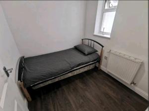 a small bed in a room with a window at Spacious 2BDR Apartment, WIFI+ Great TV in Romford