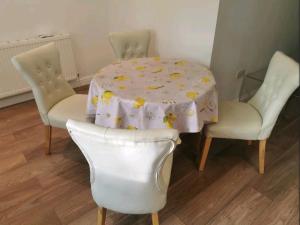 Spacious 2BDR Apartment, WIFI+ Great TV في رومفورد: طاولة بيضاء مع كرسيين وطاولة مع قطعة قماش