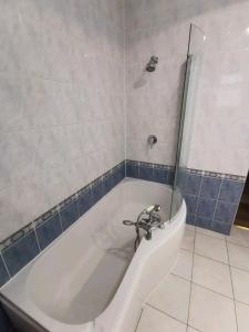 Spacious 2BDR Apartment, WIFI+ Great TV في رومفورد: حمام مع حوض استحمام مع باب زجاجي
