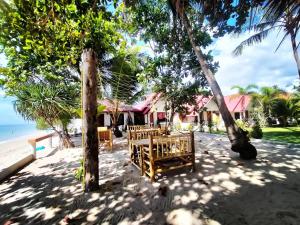 a table and chairs under trees on the beach at Lanta Beach Resort in Ko Lanta