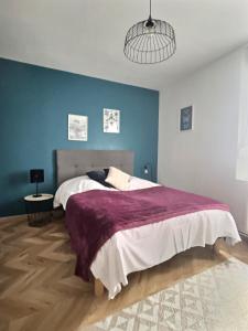 - une chambre avec un grand lit et une couverture violette dans l'établissement Les Recollets, à Châlons-en-Champagne