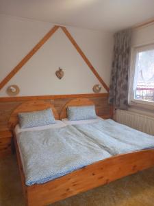 Schlafzimmer mit einem Holzbett mit blauer Bettwäsche und einem Fenster in der Unterkunft Wald-Landhaus in Hahnenklee-Bockswiese