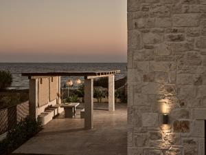 a stone building with a pathway next to the ocean at LaTerre Villa, Zante Zen By ThinkVilla in Psarou