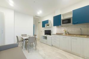 une cuisine avec des placards bleus et une table avec des chaises dans l'établissement Residence Flow-R, à Riccione