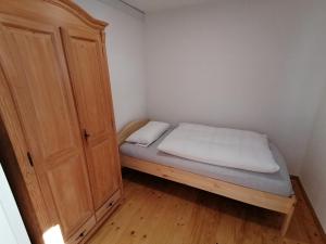 a small bedroom with a bed and a wooden cabinet at Ferienhaus Regina in Neudorf
