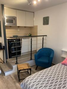 ein Schlafzimmer mit einem Bett und einem blauen Stuhl sowie eine Küche in der Unterkunft Apartment Eden Park in Saint-Tropez