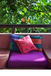 deux oreillers colorés assis sur un banc violet dans l'établissement Biancas Garden Apartments Boracay, à Boracay