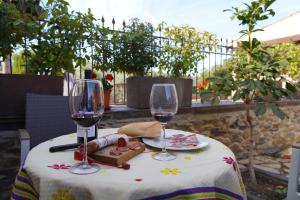 stół z dwoma kieliszkami do wina i talerzem jedzenia w obiekcie Los Monteros Sierra de Francia w mieście Aldeanueva de la Sierra