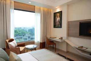 a hotel room with a bed and a desk and a window at The Greenwood Guwahati - A Luxury Boutique Hotel in Guwahati