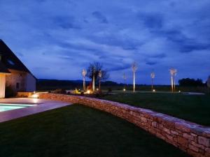 a stone retaining wall next to a yard at night at Domaine du moulin de Jeanne in Courlaoux