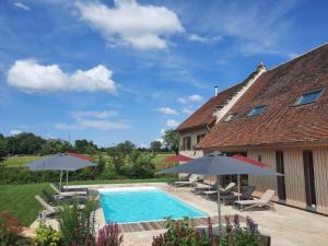a house with a swimming pool and umbrellas at Domaine du moulin de Jeanne in Courlaoux