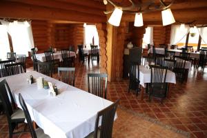 a dining room with white tables and black chairs at Székelyföld Fogadó in Borzont +29 photos