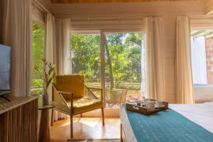 a bedroom with a bed and a chair and a window at Larisa Resort Ashwem in Mandrem